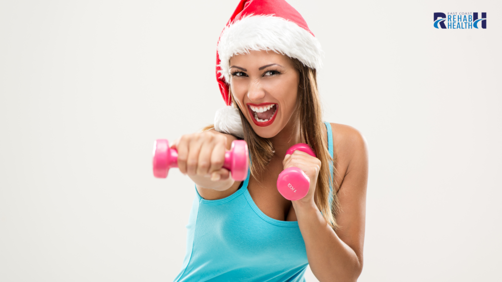 Woman wearing a Santa hat performing a light dumbbell workout, smiling during a festive Stress Free Season fitness session